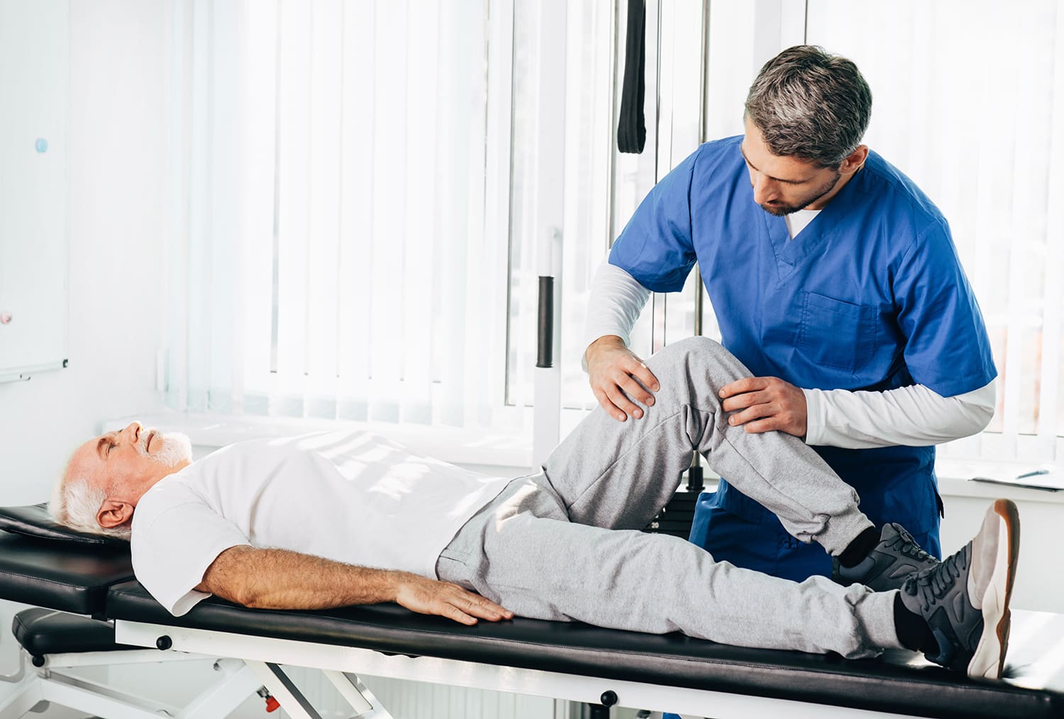 A chiropractic professional manipulating a patient's knee.