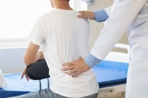 A shoulder pain chiropractor in Mechanicsburg, PA adjusting the spinal column of a seated client.