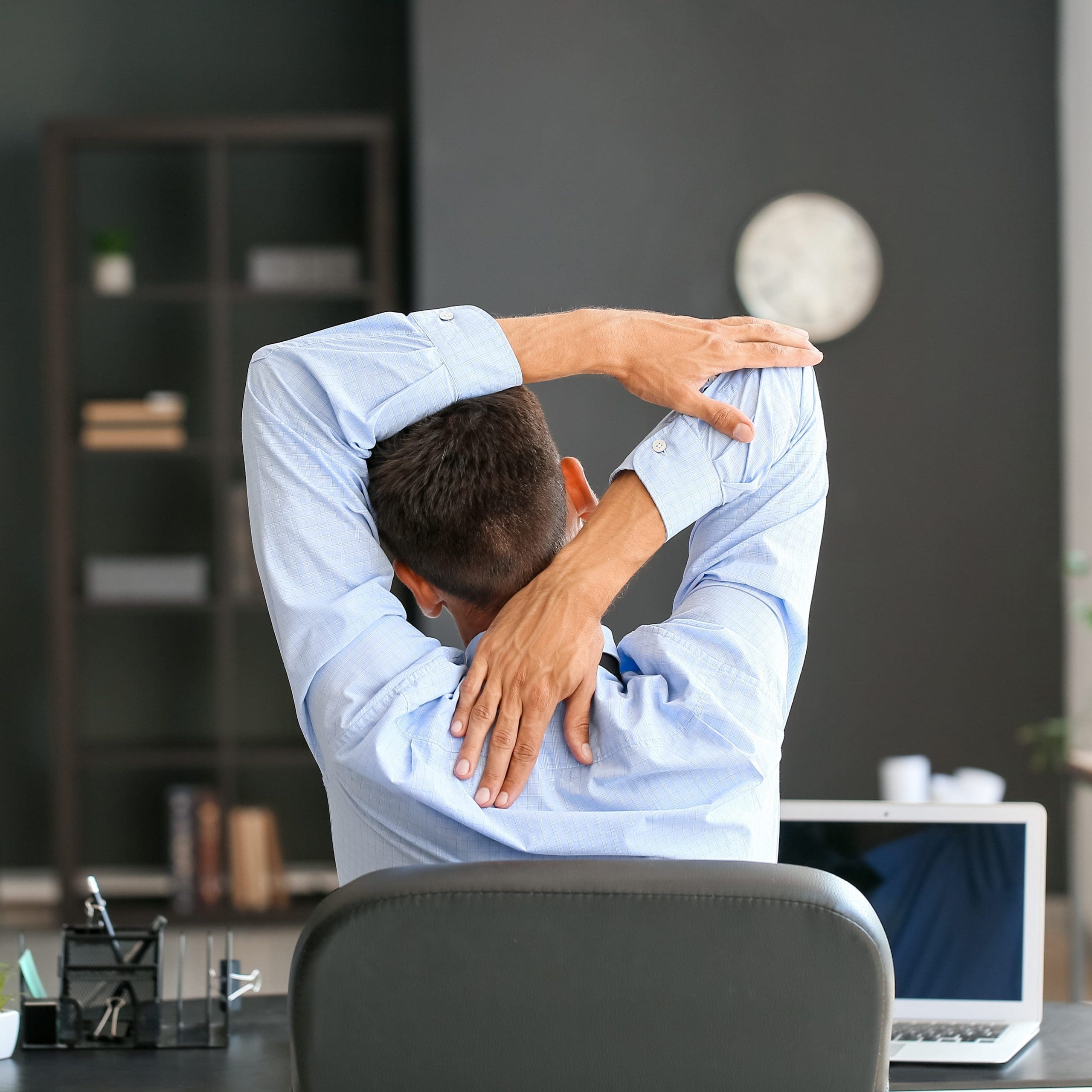 A man stretching in his office chair.